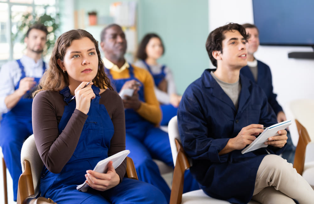 During lecture meeting, group of worker listen to teacher and write down summary