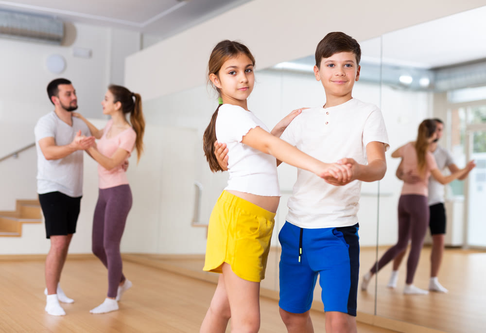 Teen sister and brother learning to dance waltz in pair in studio