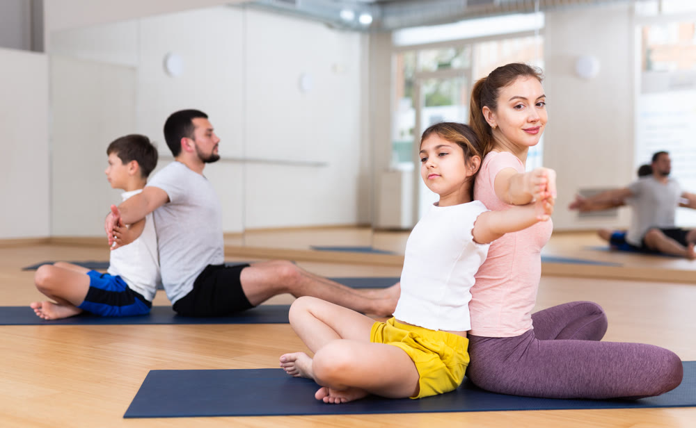 Teen girl practicing partner yoga in pair with mother during family training