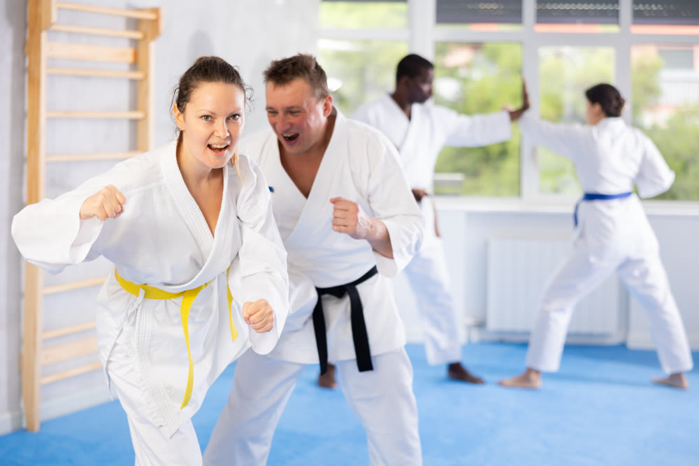 Woman and man in kimono sparring in gym during karate training