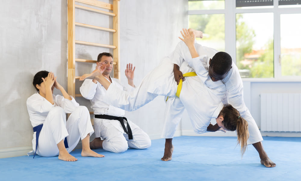 Middle-aged man applying throwing technique on his opponent in sports hall