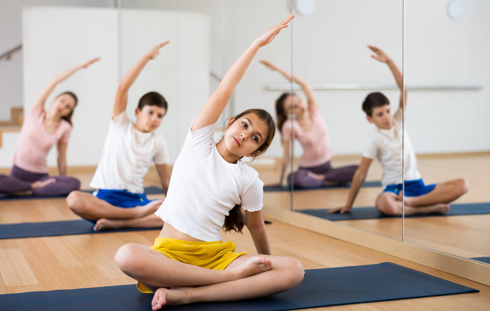 Preteen girl stretching in lotus position during family training