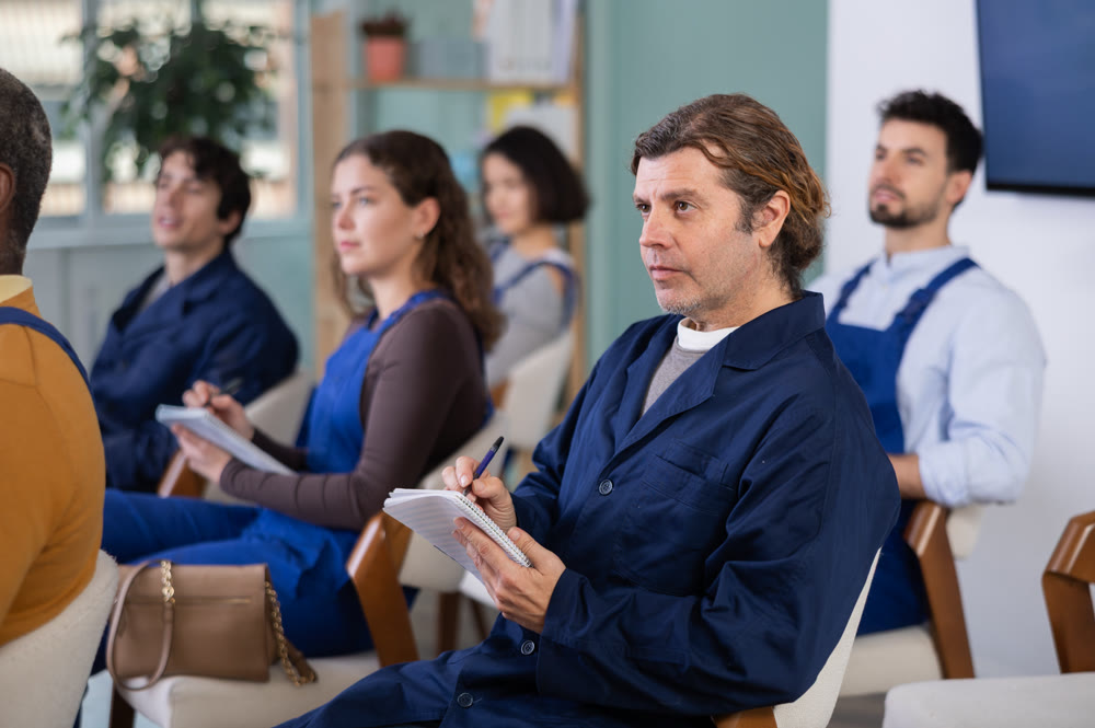 During lecture meeting, middle age man worker listen to teacher and write down summary