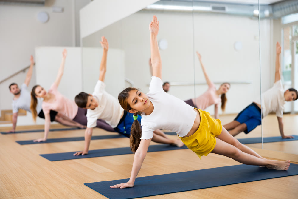 Preteen girl practicing Vasisthasana or Side Plank pose during family yoga workout