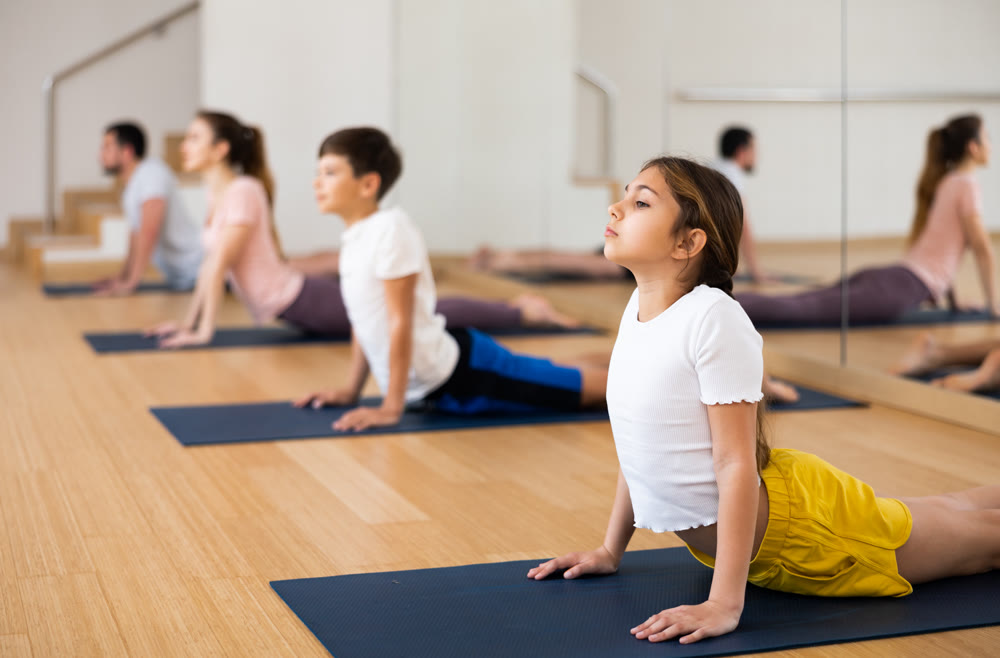 Girl exercising cobra pose during family yoga training