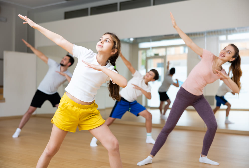 Happy girl practicing dynamic choreography with family in dance studio