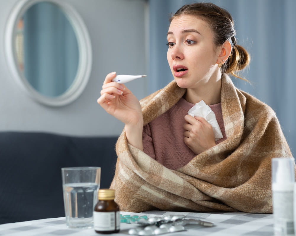 Woman with fever symptoms sitting at home