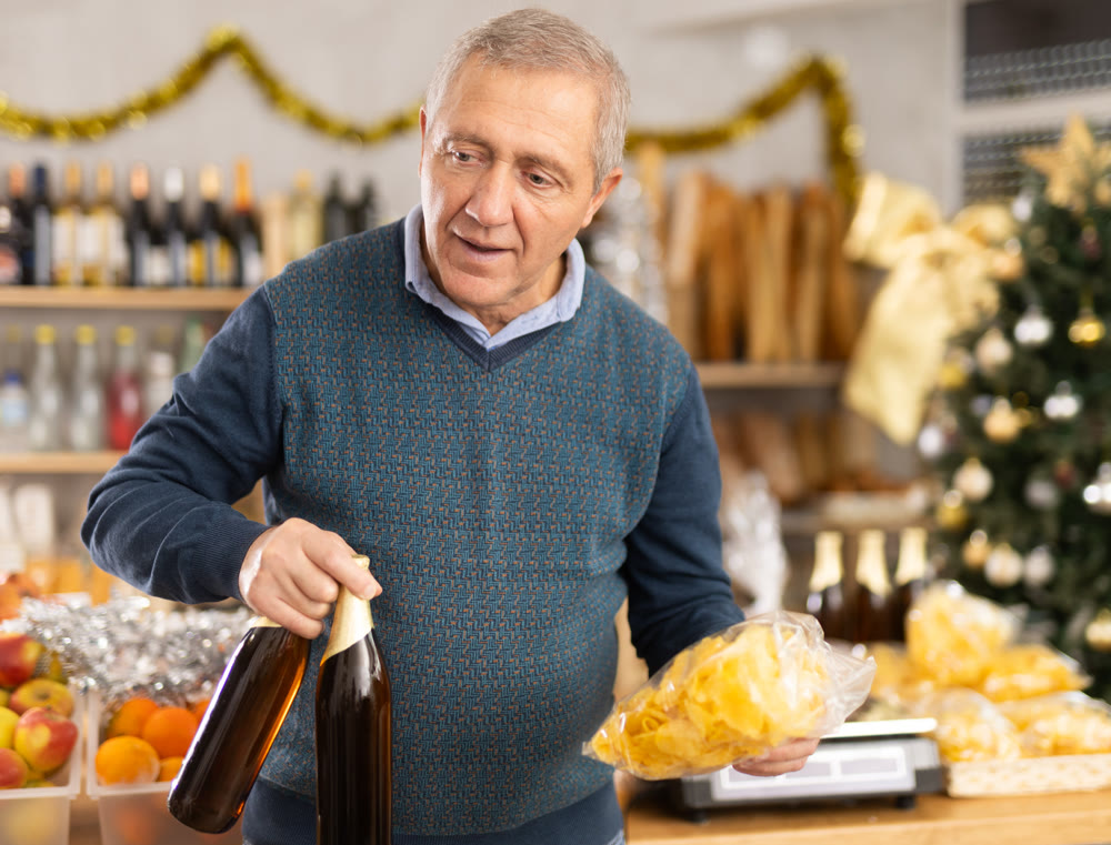 Elderly man chooses beer and chips at grocery store