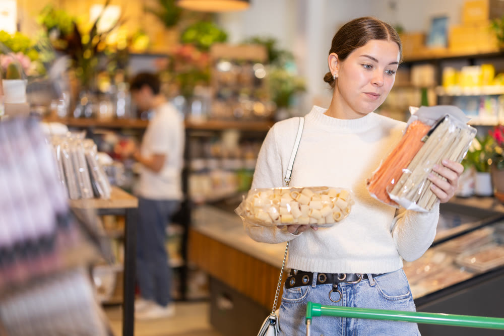 Young woman choosing pasta in grocery supermarket