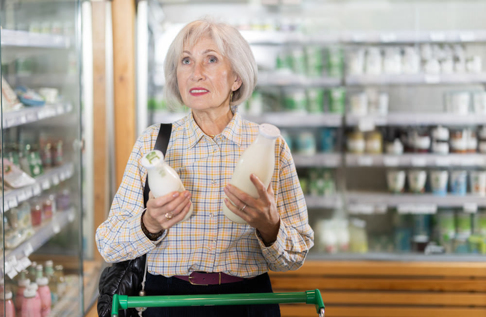 Young woman choosing milk in grocery supermarket