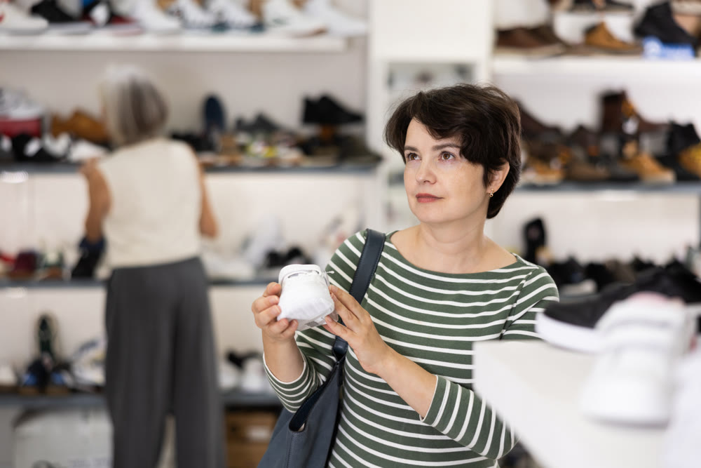 Adult woman chooses sneakers in shoe store