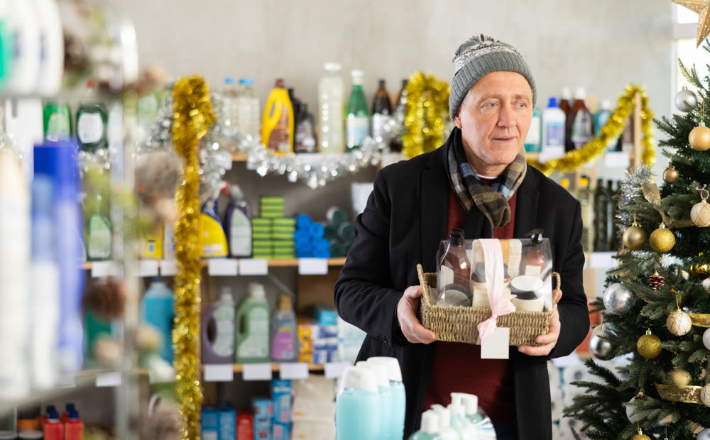 Elderly man choosing a festive shower set in a Christmas supermarket