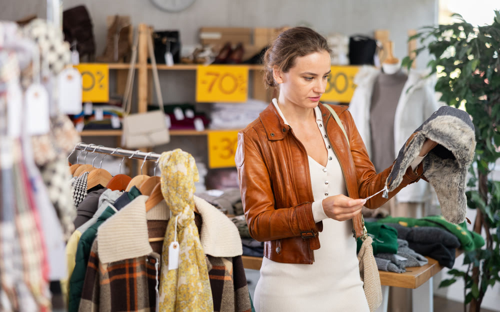 Young woman choosing fur hat in clothing store