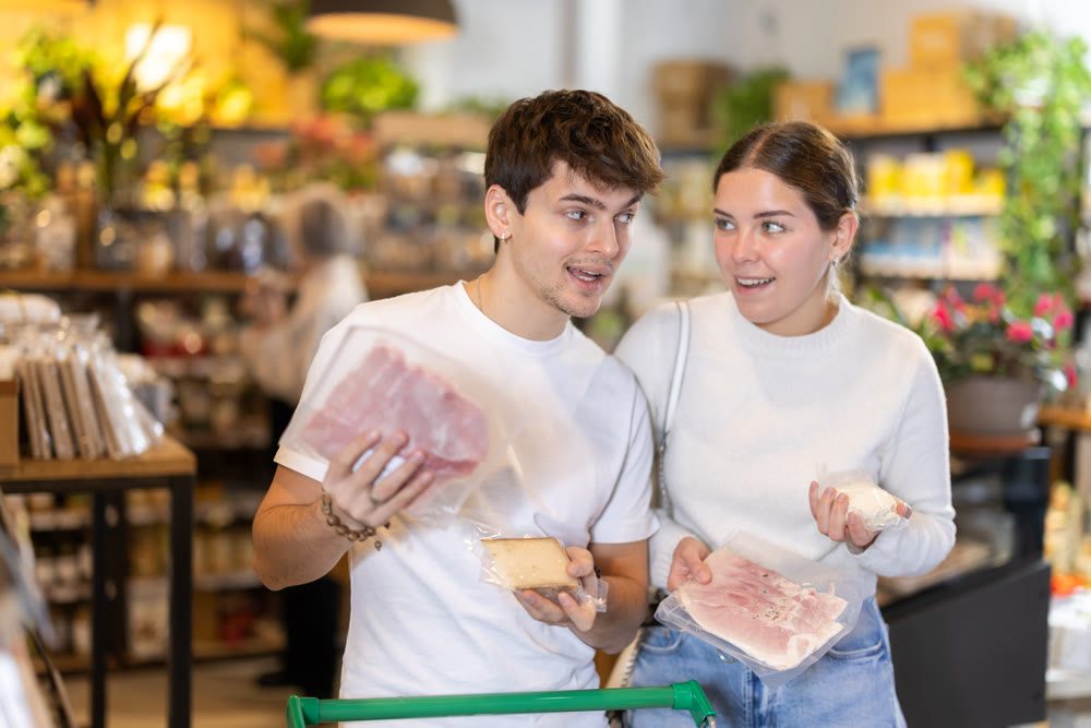 Couple choosing cheese and bacon at the supermarket