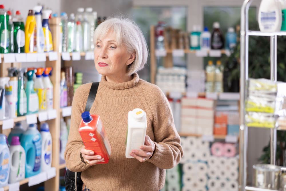 Elderly female customer diligently picking out dishwashing liquid
