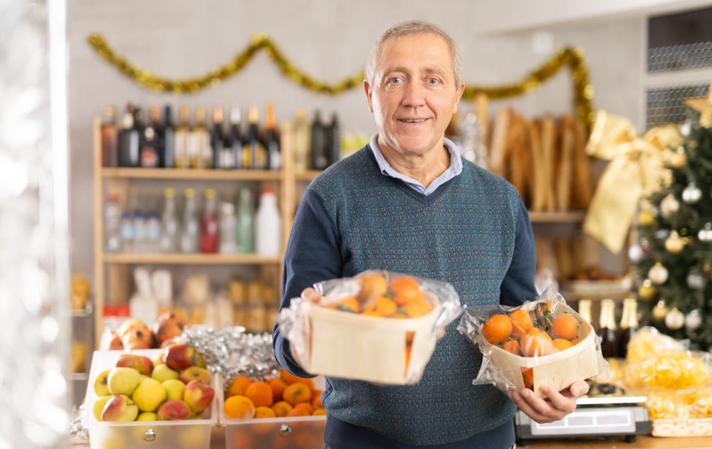 Elderly man chooses tangerines in grocery store