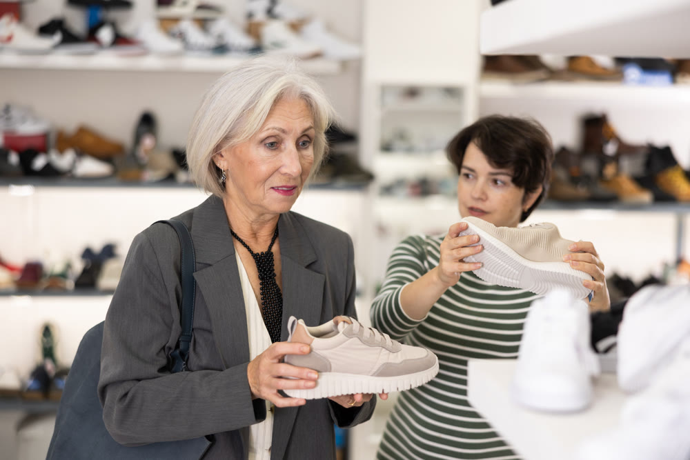 Two women are shopping in shoe store, choose snickers