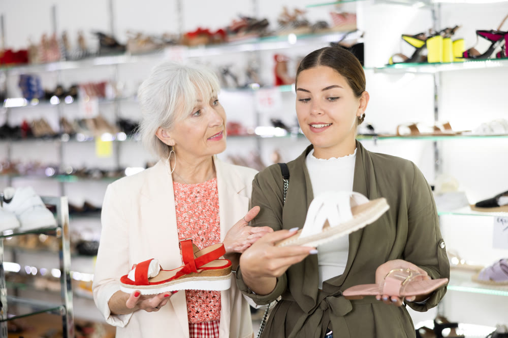 Two female friends and colleagues consult with each other about buying flip-flops or sandals