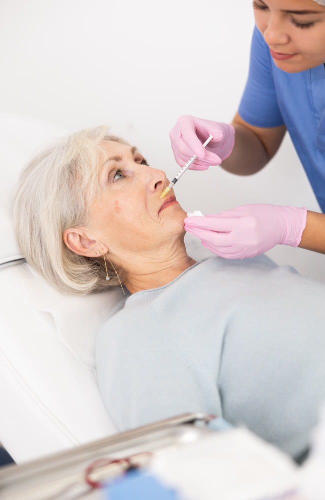 Old woman having mesotherapy procedure on her face
