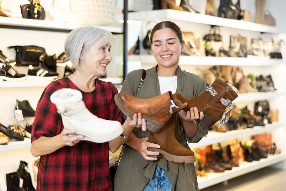 Two female shoppers discussing models of demi-season boots in store