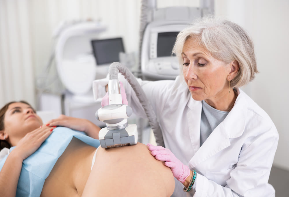 Old woman specialist doing LPG massage of hips of young woman