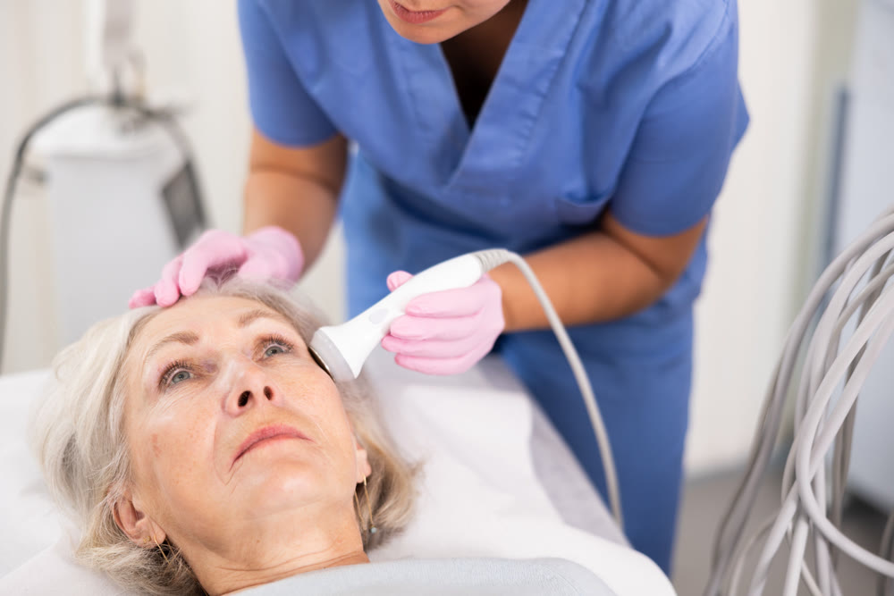 Old woman having face laser therapy procedure