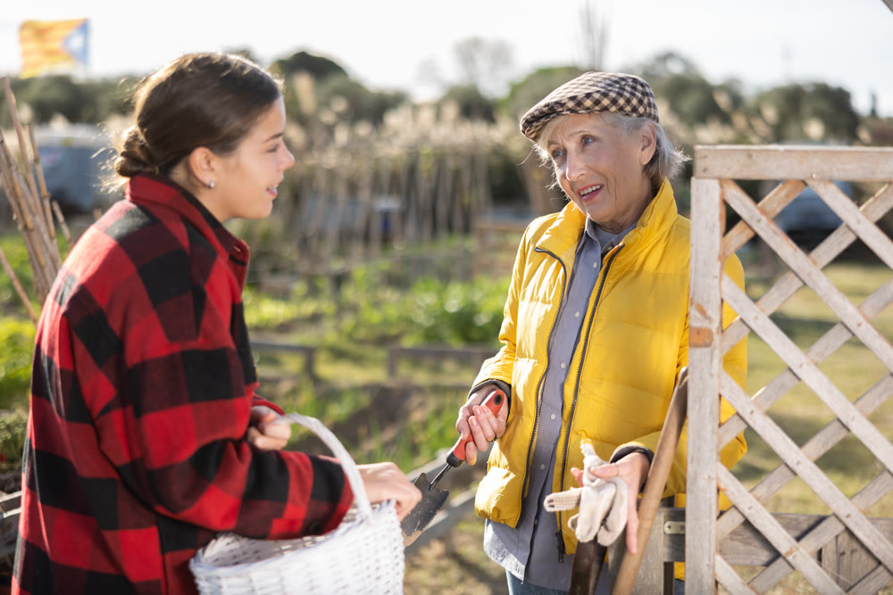 Female farmers friendly talking outside next to wooden fence on background with farm