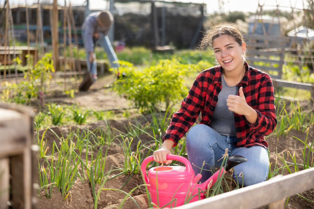 Portrait of an satisfied woman with watering can for watering plants in garden