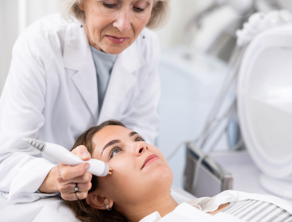 Young woman having face radiolifting procedure made by doctor