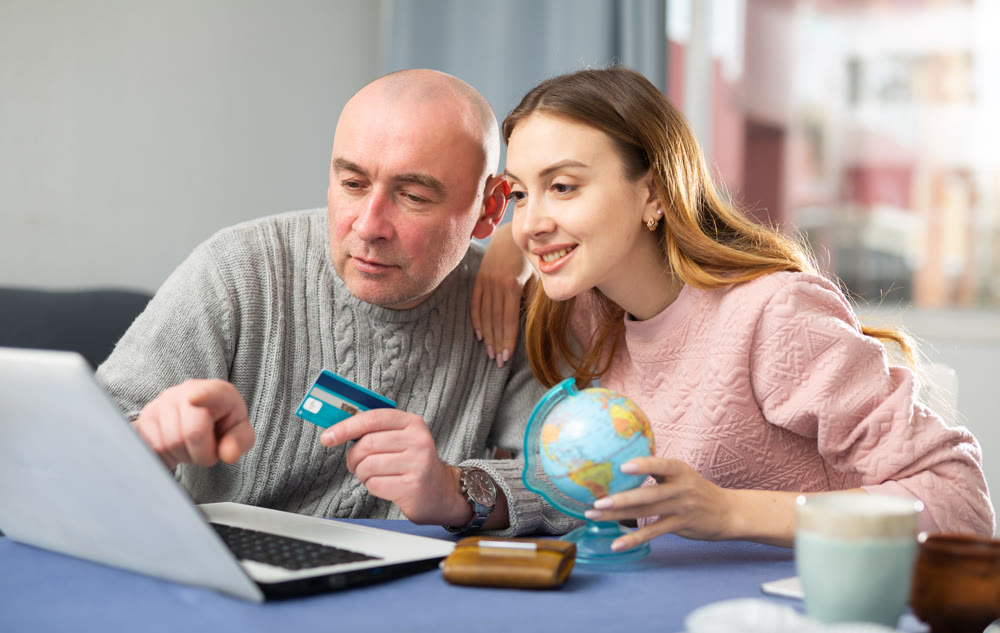Happy married couple book a vacation tour on a laptop