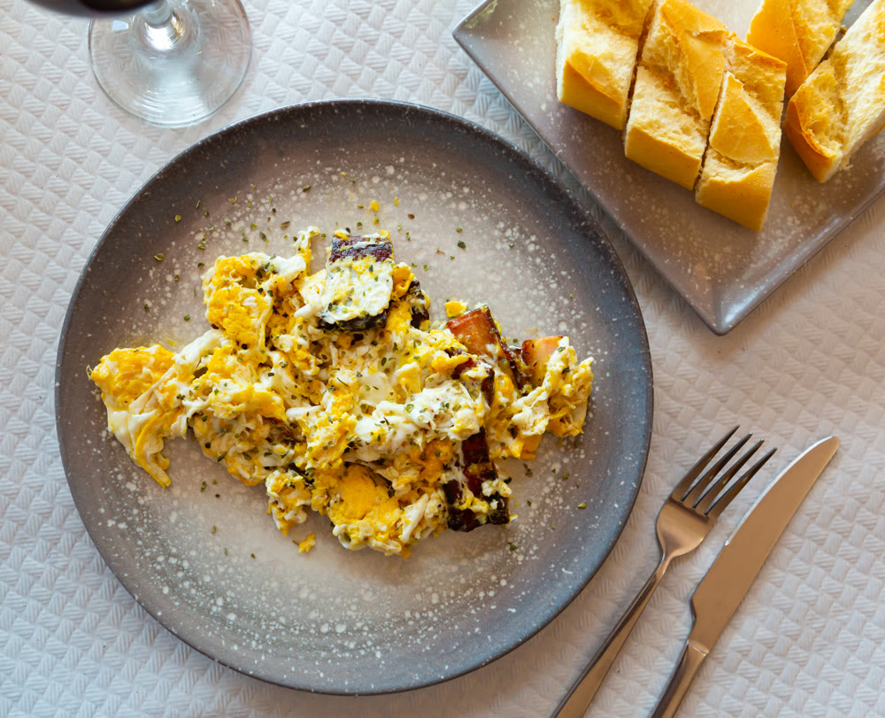 Delicious breakfast in cafe of scramble eggs with pork pieces closeup