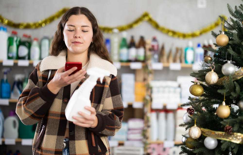 In Christmas decorated shop, woman client scanning QR code on package paint remover