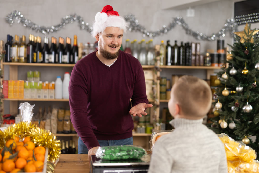 Man seller weighs candies for boy buyer