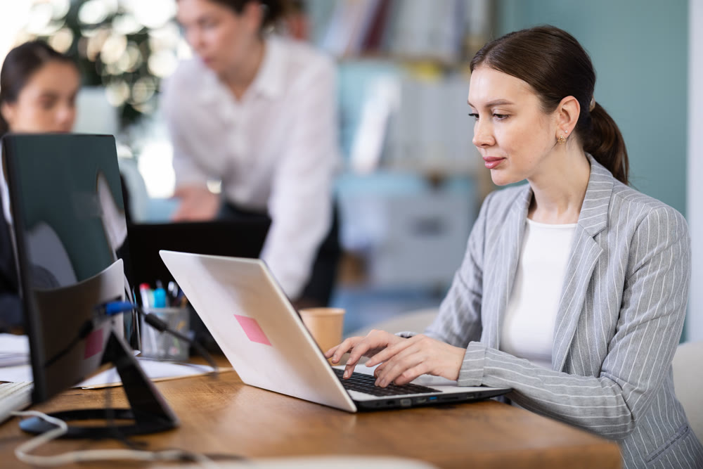 Focused young woman working on laptop during busy corporate session