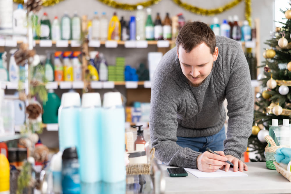 Middle-aged man restocking using paper in store with New Year decoration