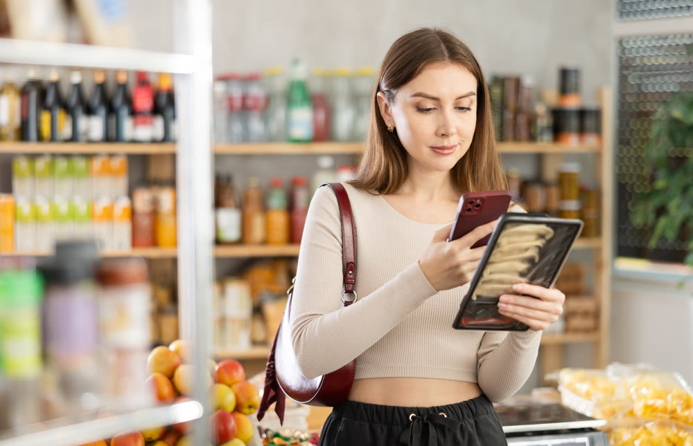 Young girl is scanning QR on a package of Juaozi in grocery store