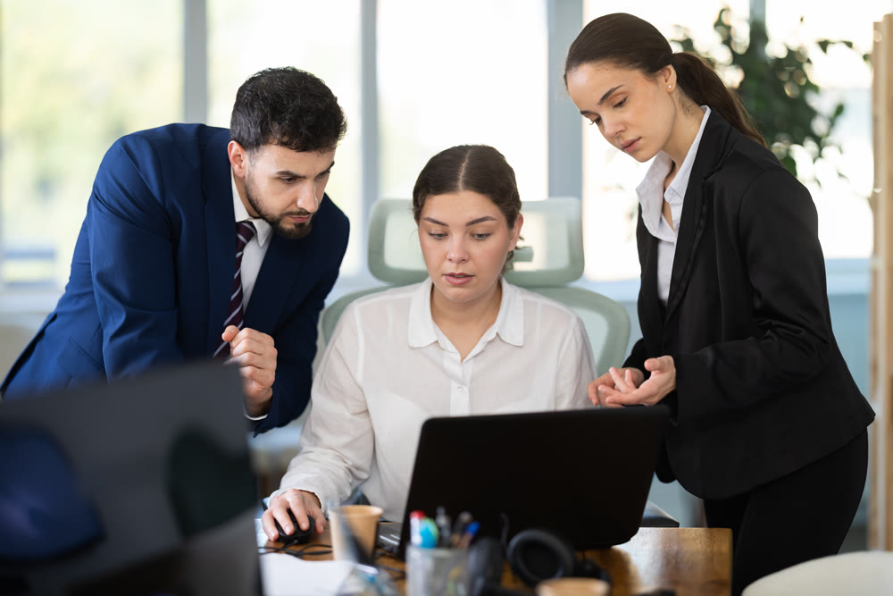 Experienced female employees work on a laptop together with a man,