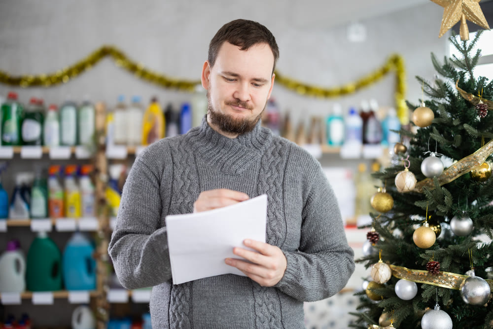 Middle-aged man restocking using paper in store with New Year decoration