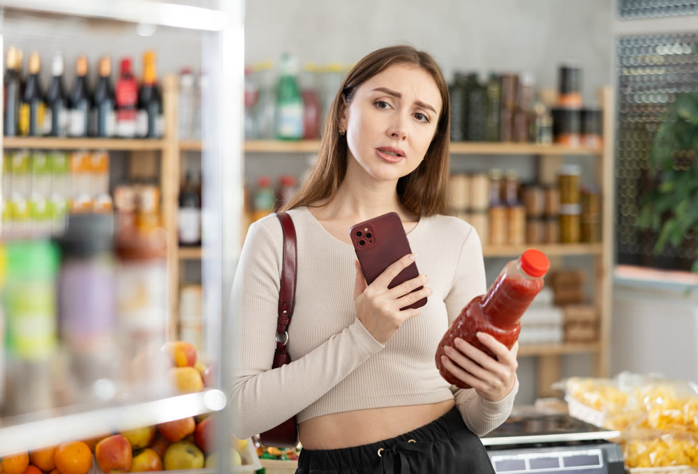 Young woman scanning qr code of tomato juice
