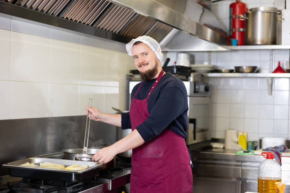 Production of semi-finished products - an employee of a food factory prepares food on oven