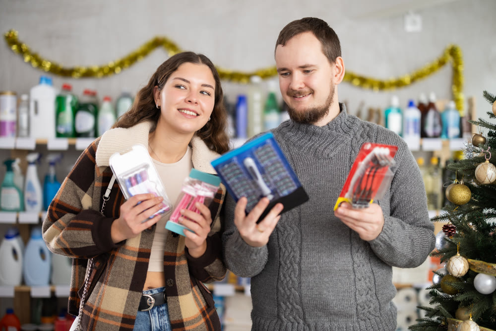 Happy couple choosing razors in Christmas decorated personal care store