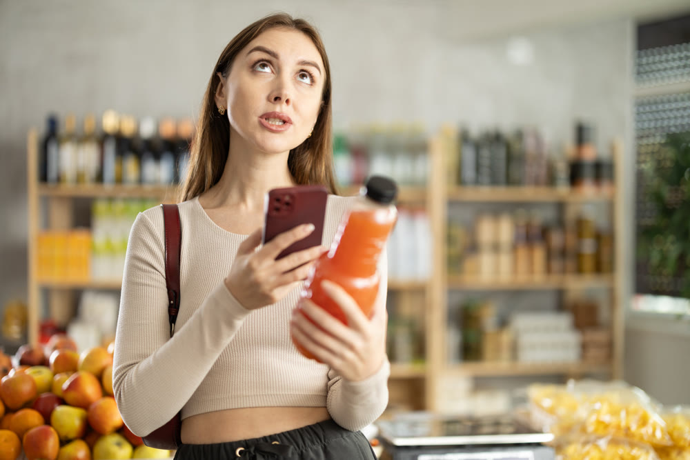 Young woman scanning qr code of grapefruit juice