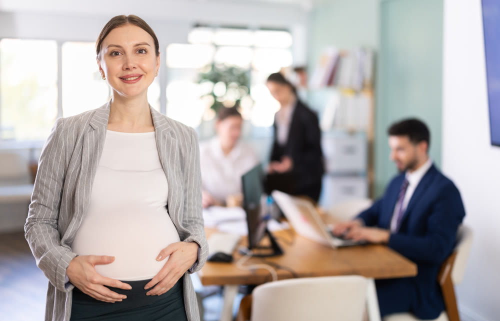 pregnant woman standing in the middle of the office, she works for the company