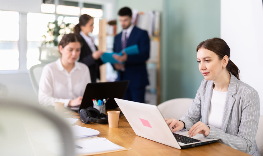 Focused young woman working on laptop during busy corporate session