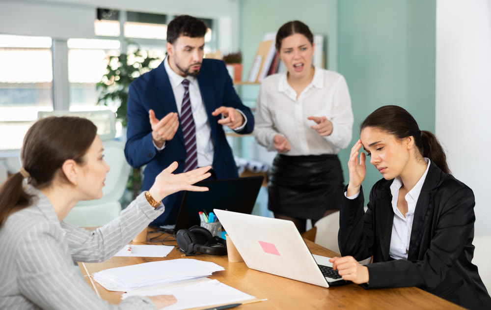 Group of colleagues scolding sad woman in office