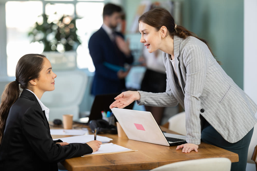 Employee helps an intern with documents against the background of the office
