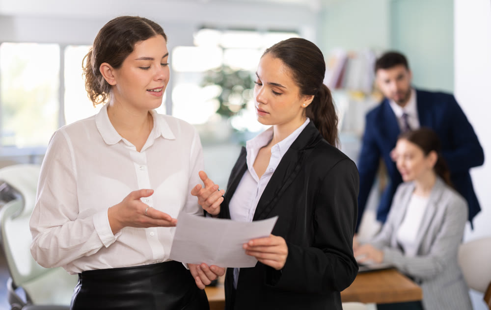 Two qualified female employees discussing work tasks