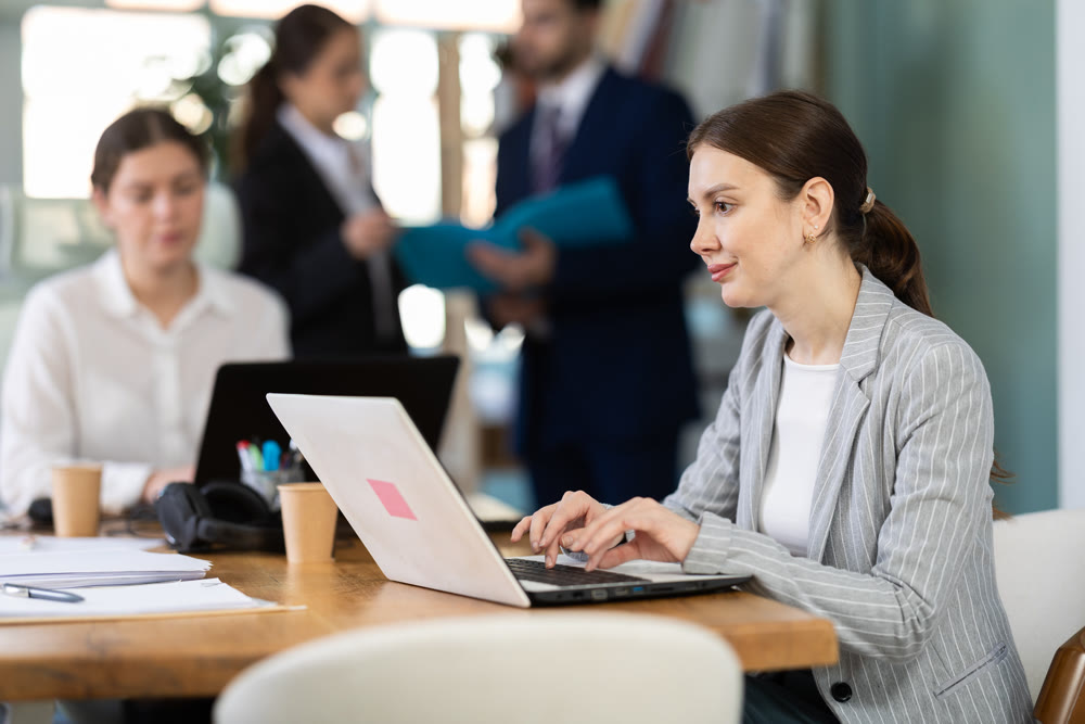 Focused young woman working on laptop during busy corporate session