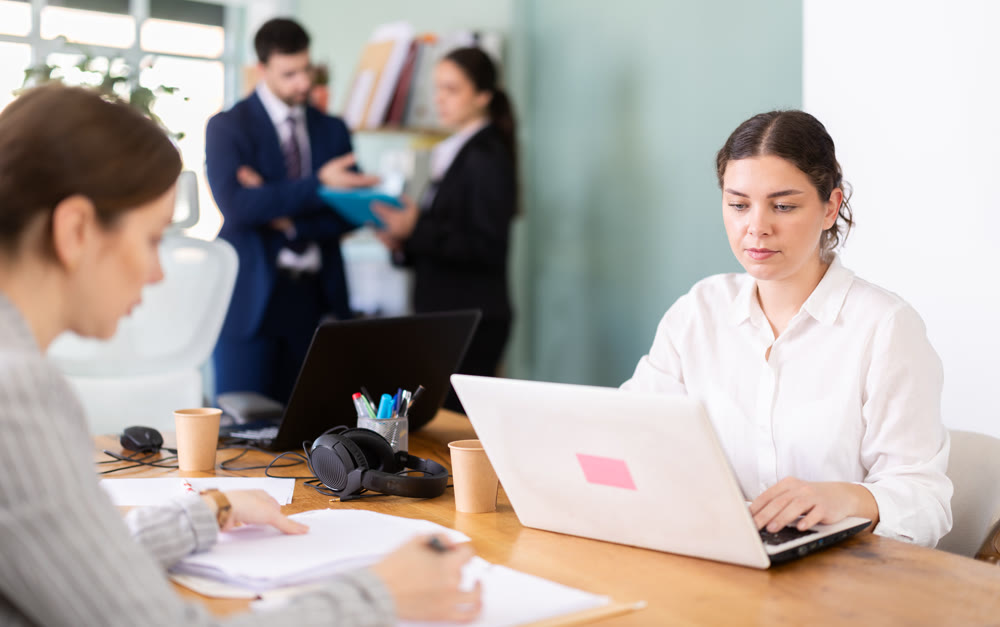 Focused young woman working on laptop during busy corporate session