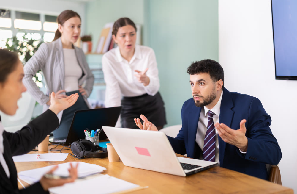 Group of colleagues scolding sad man in office